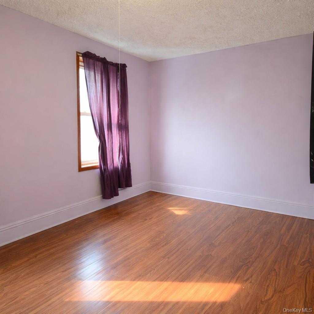 91-45 85th Street Queens, NY 11421 - Photo 2 of 15 a view of an empty room with wooden floor and window