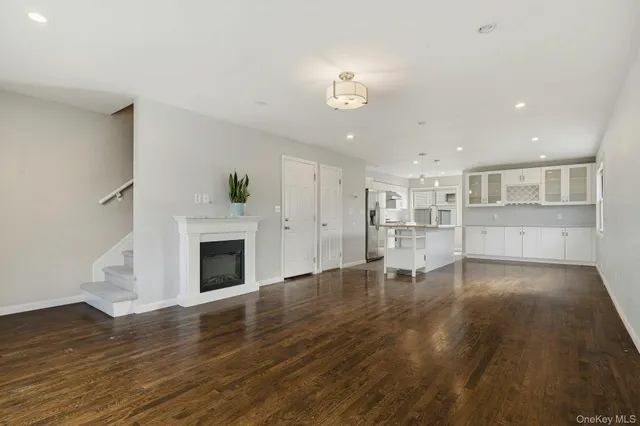 a view of a livingroom with wooden floor and a kitchen