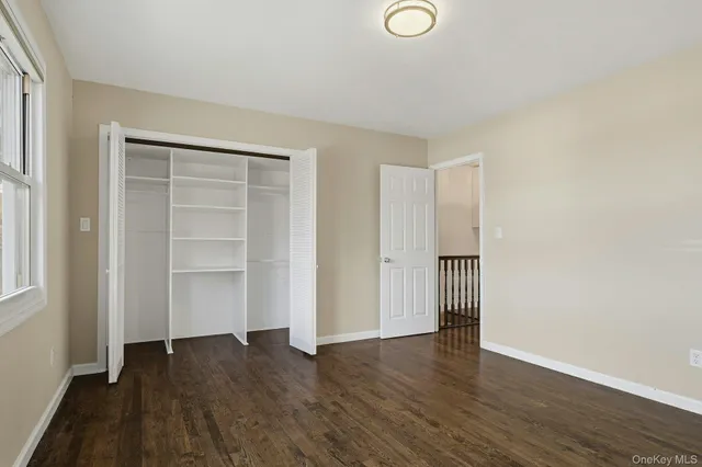 an empty room with wooden floor & closet and windows