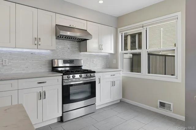 a kitchen with stainless steel appliances granite countertop white cabinets and a stove