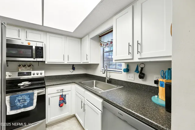 a kitchen with stainless steel appliances granite countertop a sink a stove and cabinets