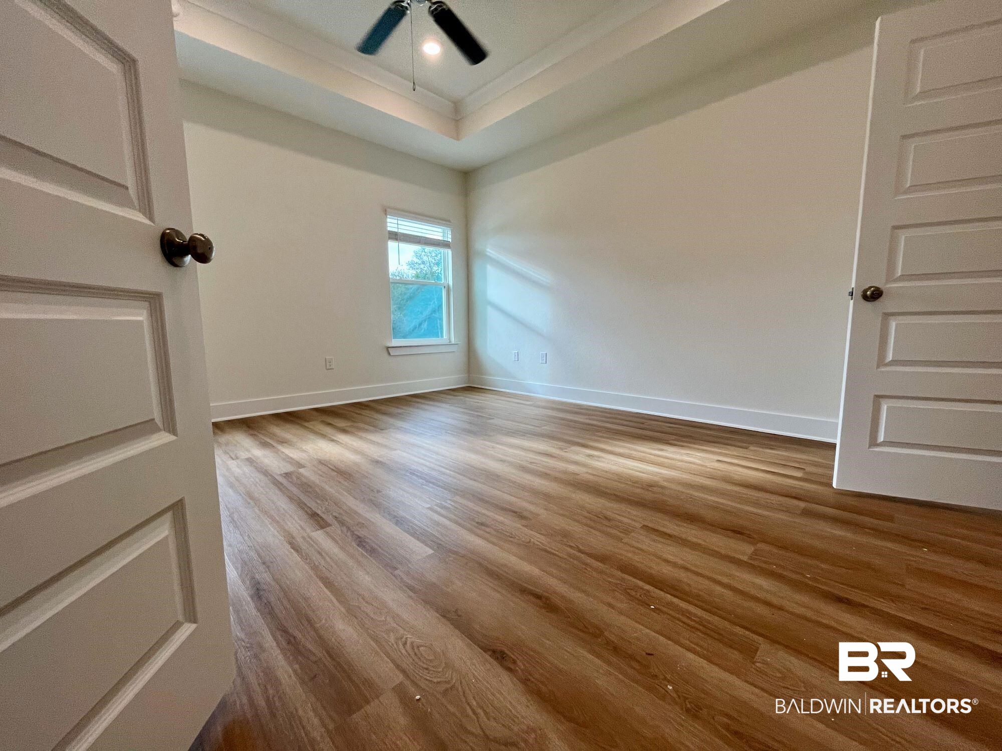 337 Barndling Street Fairhope, AL 36532 - Photo 23 of 34 Empty room featuring ceiling fan, light hardwood / wood-style flooring, crown molding, and a tray ceiling