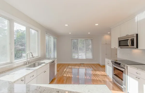 a kitchen with granite countertop a stove a sink and a microwave