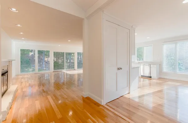 a view of an empty room with wooden floor and a window