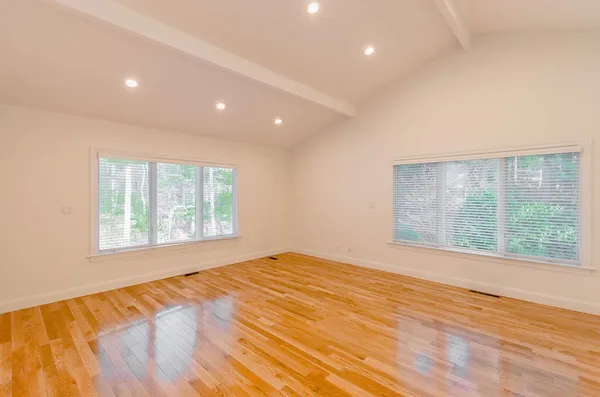 a view of an empty room with wooden floor and a window