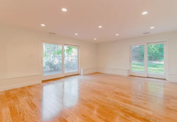 an empty room with wooden floor and windows
