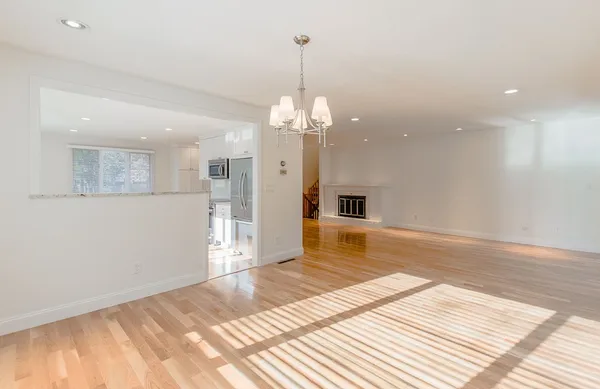 a view of a livingroom with a chandelier fan and kitchen view
