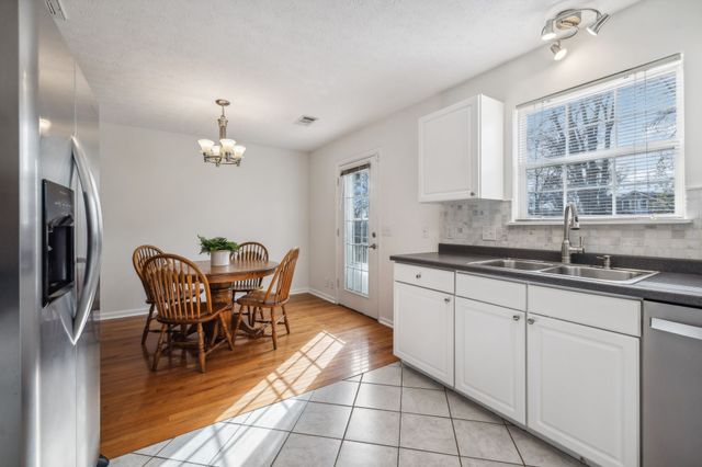 a kitchen with stainless steel appliances granite countertop a sink a stove a dining table and chairs