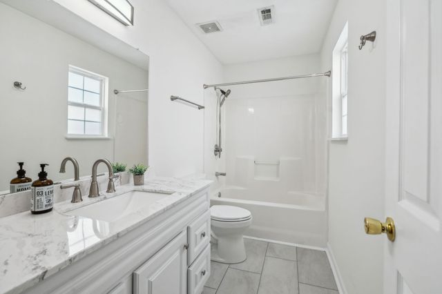 a bathroom with a granite countertop sink a toilet and shower