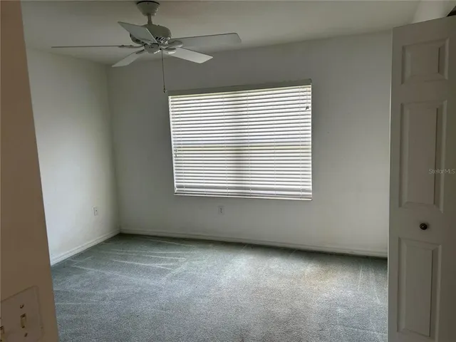 an empty room with a window and a fan
