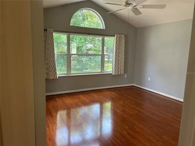 a view of an empty room with wooden floor and a window