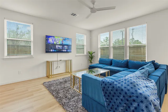 a living room with furniture two windows and a flat screen tv