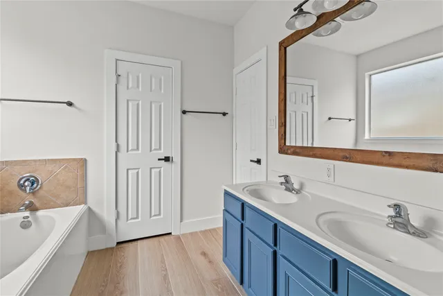 a bathroom with a tub a sink and mirror