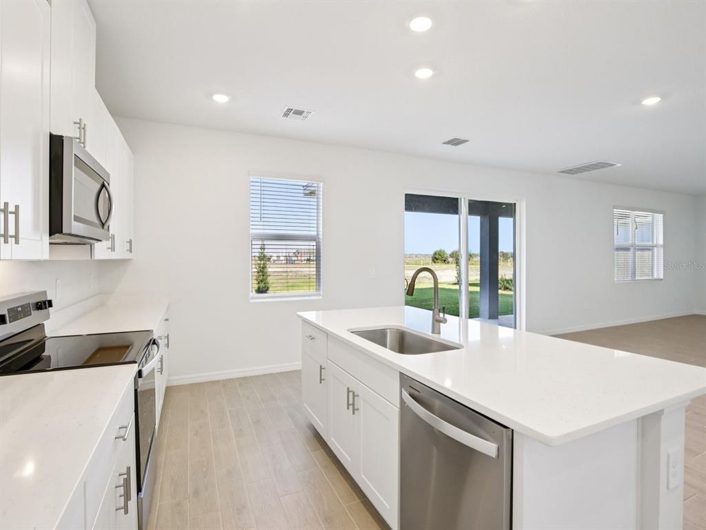 13311 Shellmore Avenue Palmetto, FL 34221 - Photo 15 of 46 a kitchen that has a lot of white cabinets and wooden floor