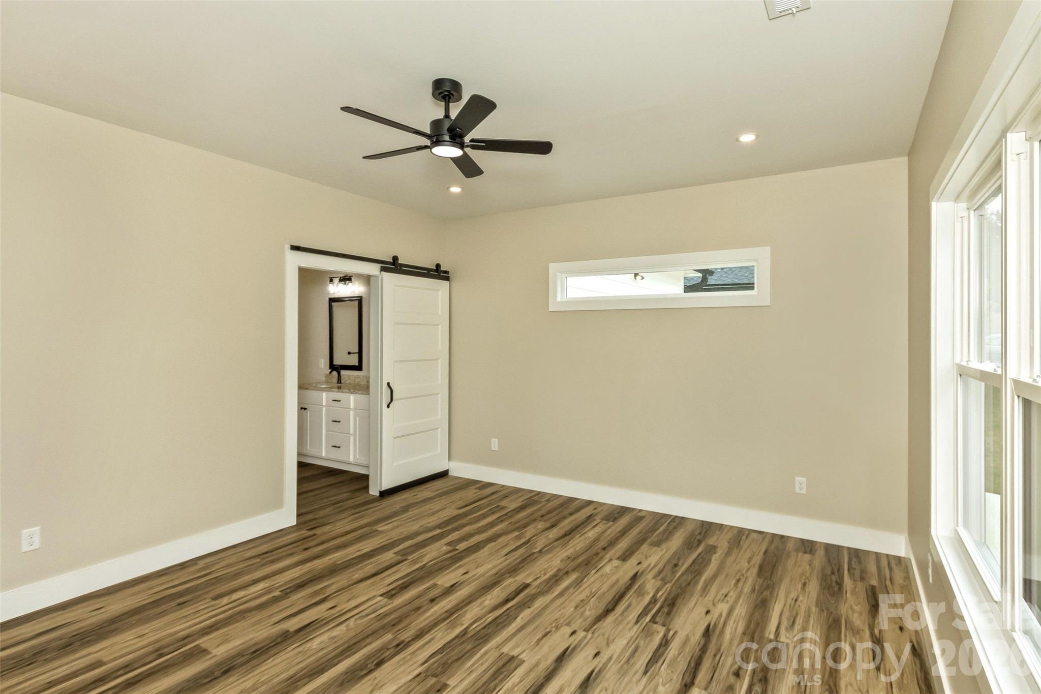 112 Peyton Elaine Road Clyde, NC 28721 - Photo 28 of 35 a view of a livingroom with wooden floor a ceiling fan and windows