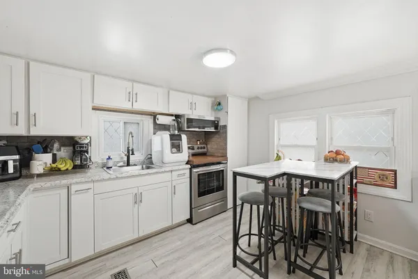 a kitchen with stainless steel appliances a refrigerator a stove a dining table and chairs with wooden floor