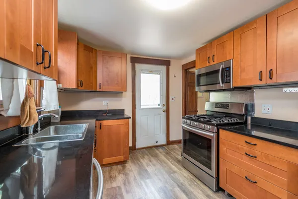 a kitchen with granite countertop wooden cabinets and a stove top oven