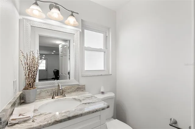 a bathroom with a granite countertop sink a toilet and mirror