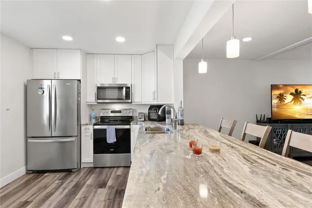 a kitchen view with stainless steel appliances wooden floor and a refrigerator
