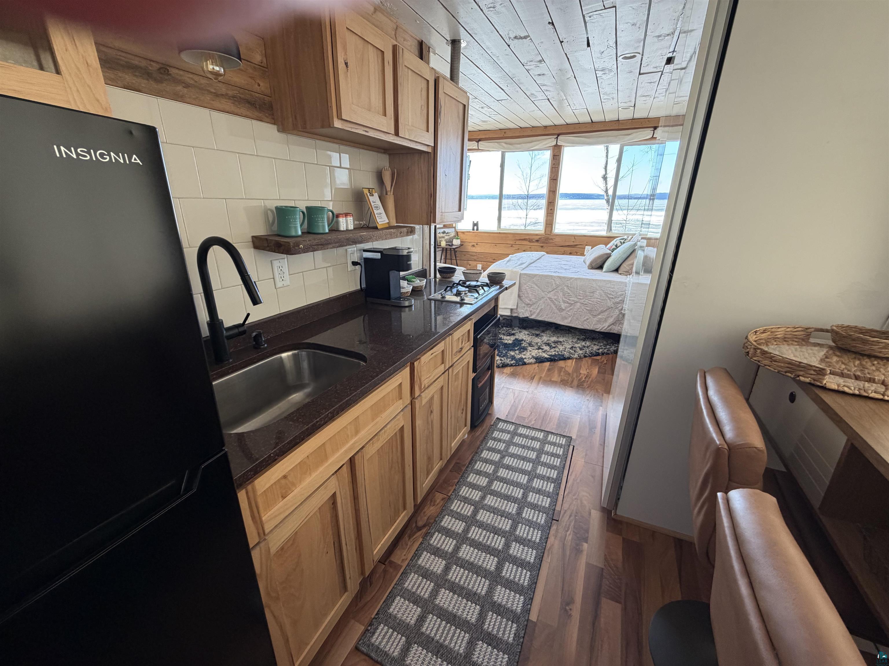 4107 A Lake Park Road Ashland, WI 54806 - Photo 5 of 12 Kitchen featuring freestanding refrigerator, dark wood finished floors, dark stone counters, wood ceiling, and tasteful backsplash