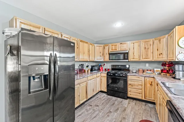 a kitchen with stainless steel appliances granite countertop a refrigerator a stove top oven a sink and dishwasher