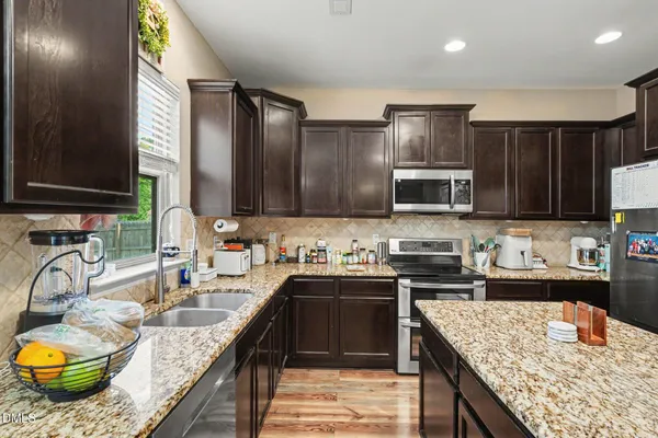 a kitchen with kitchen island granite countertop a sink stove and cabinets
