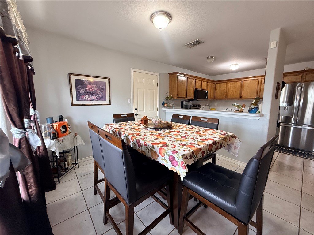 1938 El Monte Street Corpus Christi, TX 78417 - Photo 4 of 9 a kitchen with a table chairs refrigerator and cabinets