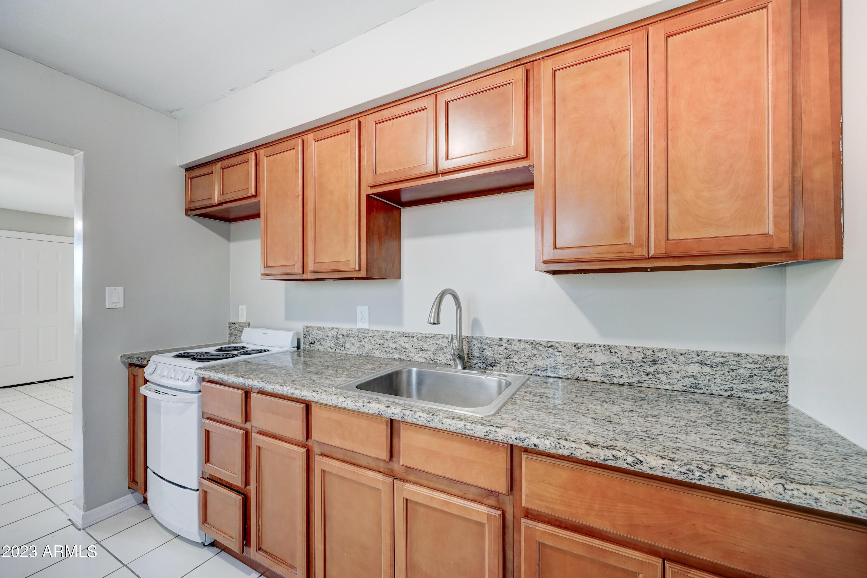 1202 North 49th Place, Unit A Phoenix, AZ 85008 - Photo 8 of 14 a kitchen with stainless steel appliances granite countertop a sink and cabinets