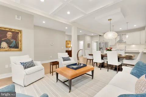 a living room with furniture kitchen view and a chandelier