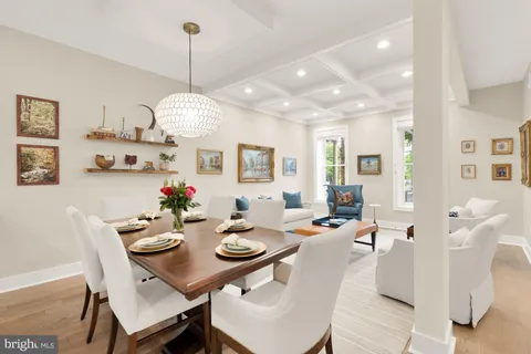 a view of a dining room and livingroom with furniture wooden floor a rug a chandelier and a mirror