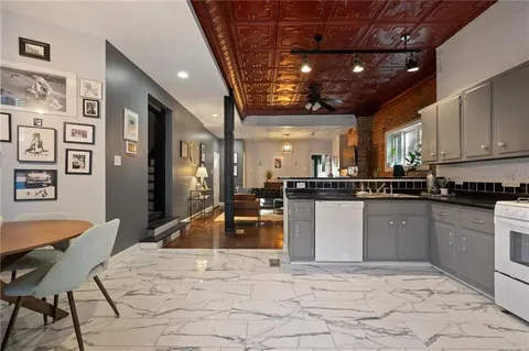 a kitchen with stainless steel appliances granite countertop a refrigerator a stove a sink a dining table and chairs with wooden floor