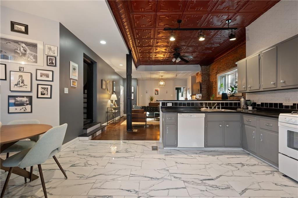 3037 Brereton Street Pittsburgh, PA 15219 - Photo 3 of 36 a kitchen with stainless steel appliances granite countertop a refrigerator a stove a sink a dining table and chairs with wooden floor