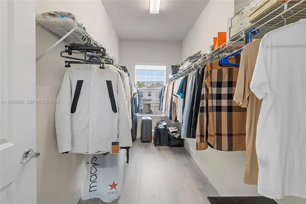 a view of walk in closet with clothes and shoes