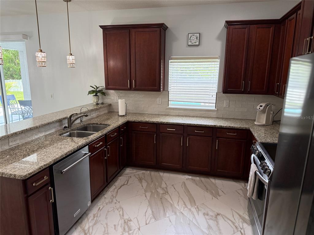 12236 Fairlawn Drive Riverview, FL 33579 - Photo 14 of 52 a kitchen with granite countertop stainless steel appliances a sink stove and cabinets