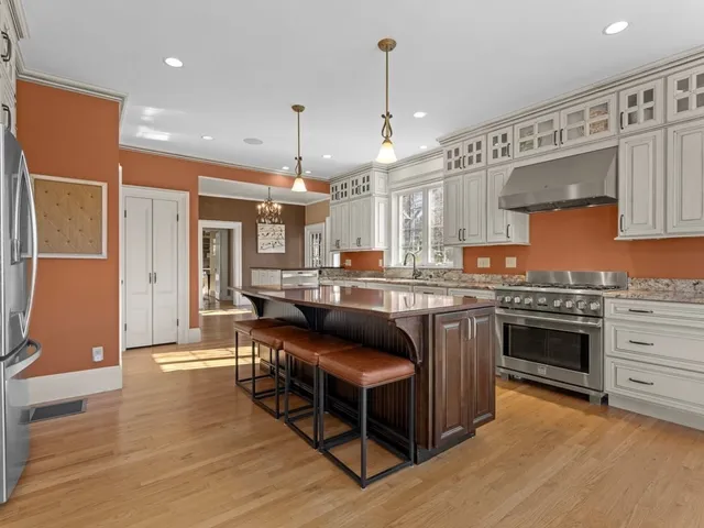 a kitchen with stainless steel appliances granite countertop a stove a sink dishwasher and a refrigerator with wooden floor