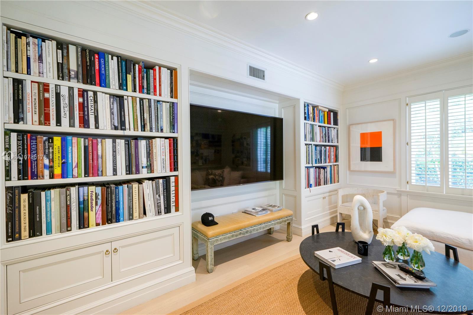 4955 Lakeview Drive Miami Beach, FL 33140 - Photo 25 of 55 a living room with furniture lots of books and a large window