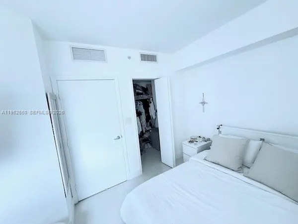 a bedroom with a bed and a refrigerator
