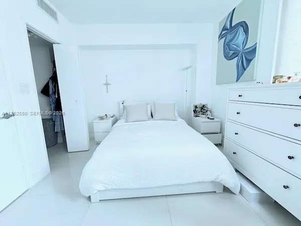 a spacious bedroom with a bed and a dresser
