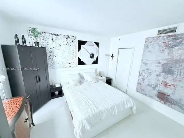 a bedroom with a bed and a refrigerator