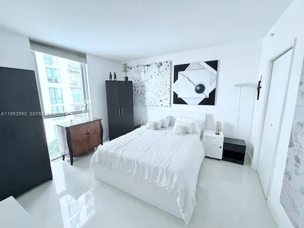 a bedroom with a bed and a refrigerator