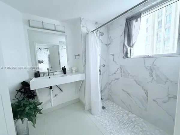 a bathroom with a sink and mirror with shower