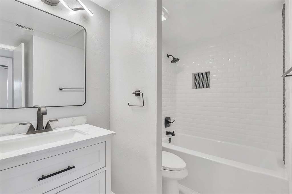4837 Cedar Springs Road, Unit 321 Dallas, TX 75219 - Photo 3 of 14 a bathroom with a sink a toilet a mirror a bathtub and shower