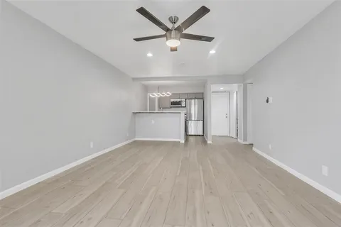 an empty room with wooden floor ceiling fan and windows