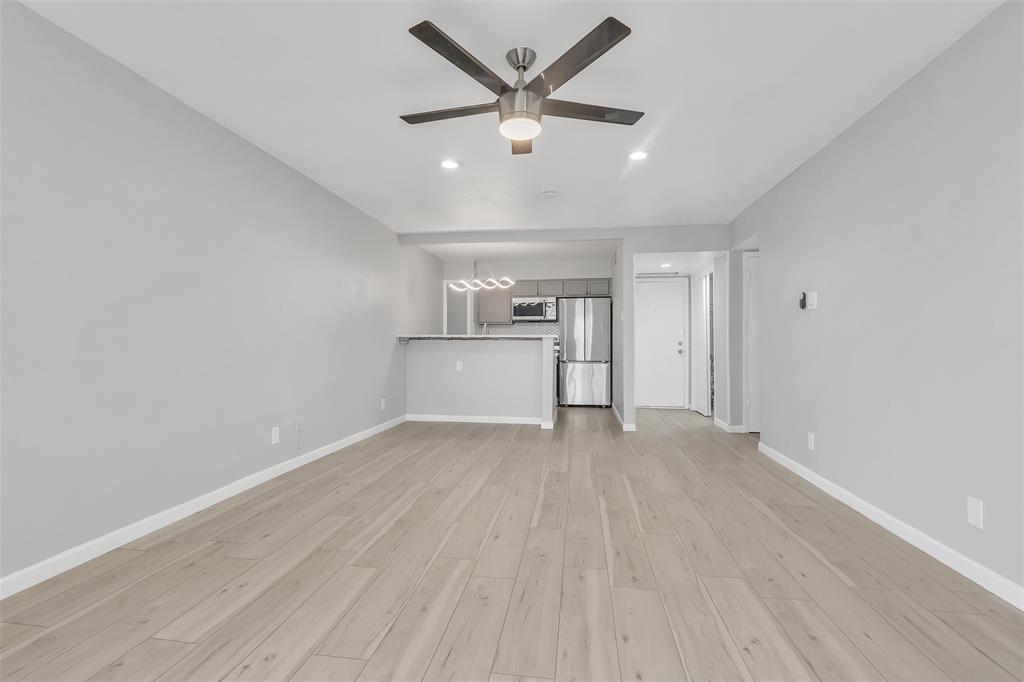 4837 Cedar Springs Road, Unit 321 Dallas, TX 75219 - Photo 5 of 14 an empty room with wooden floor ceiling fan and windows