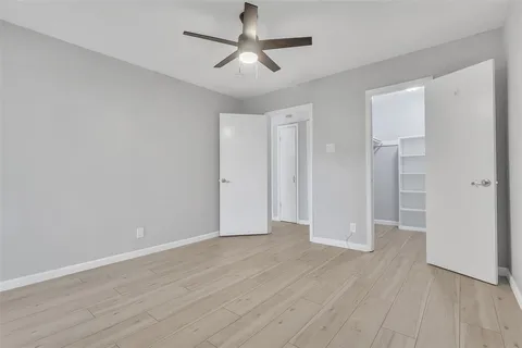 an empty room with wooden floor and ceiling fan