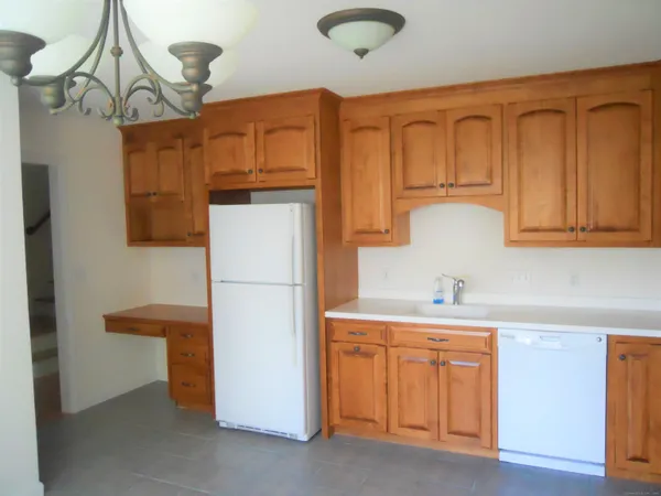 a kitchen with stainless steel appliances granite countertop a refrigerator a sink dishwasher and white cabinets with wooden floor