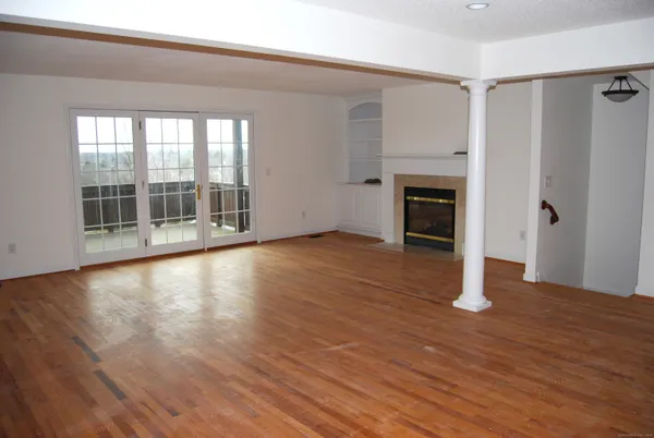 wooden floor fireplace and windows in an empty room