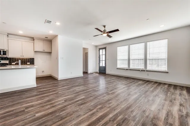 a view of an empty room with window and wooden floor