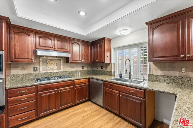 a kitchen with stainless steel appliances granite countertop wooden cabinets a sink and dishwasher
