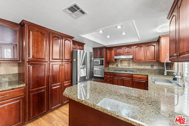 a kitchen with stainless steel appliances granite countertop a refrigerator a stove and a sink
